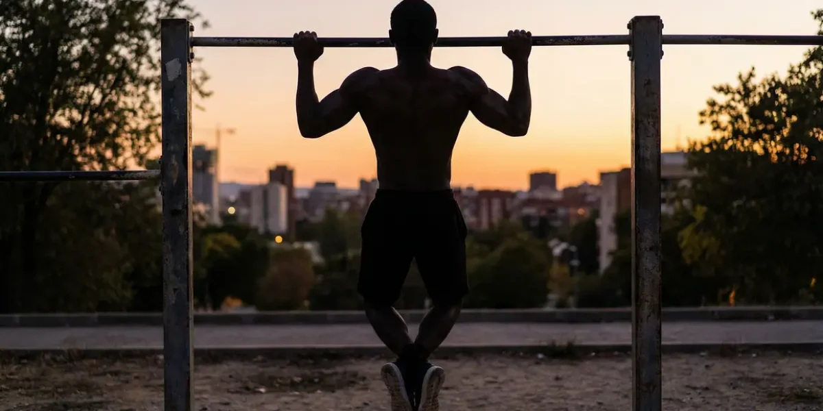 Silhouette effectuant une traction calisthenics sur barre extérieure